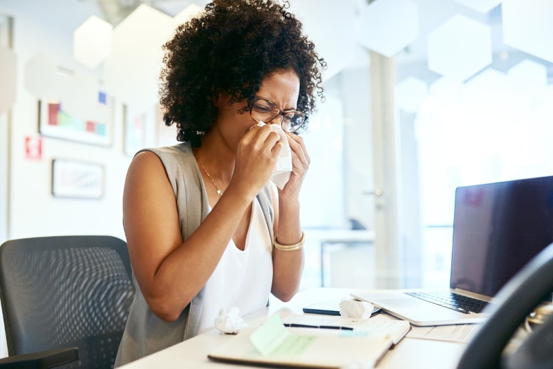 Young Woman Sneezing In Office