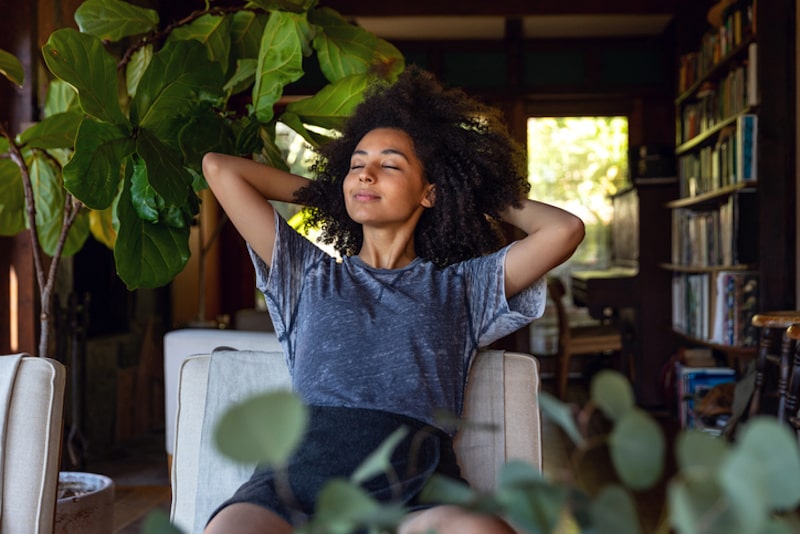 woman relaxing in chair surrounded by plants